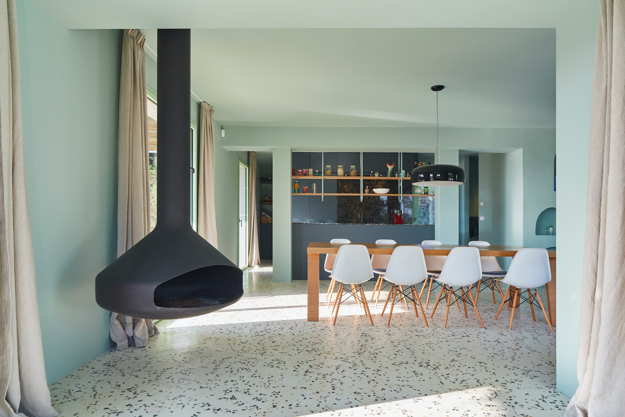 Salón comedor con chimenea suspendida y suelo de terrazo, reforma Na Xamena, Ibiza