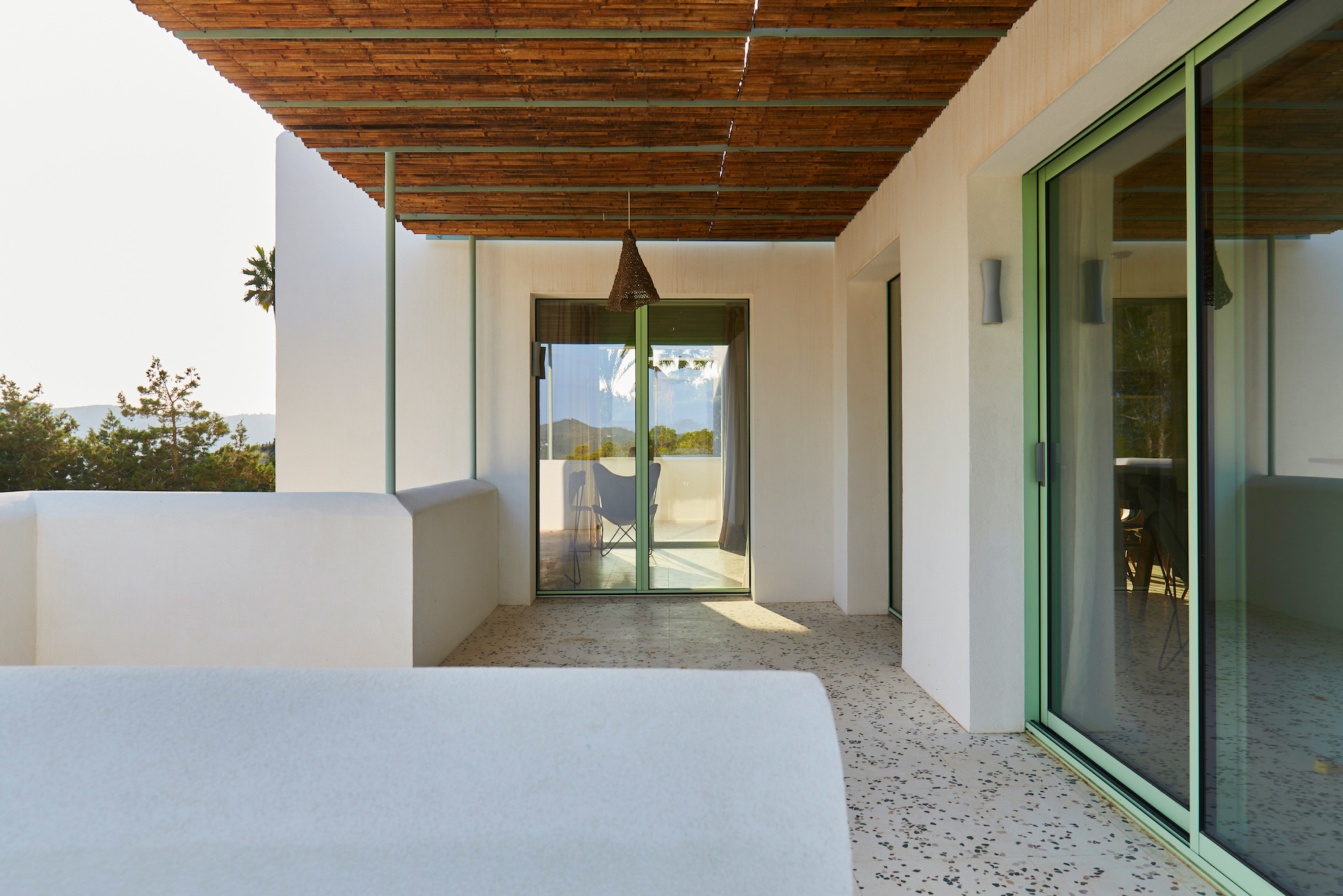 Terraza cubierta con cañizo y carpintería verde, reforma Na Xamena, Ibiza