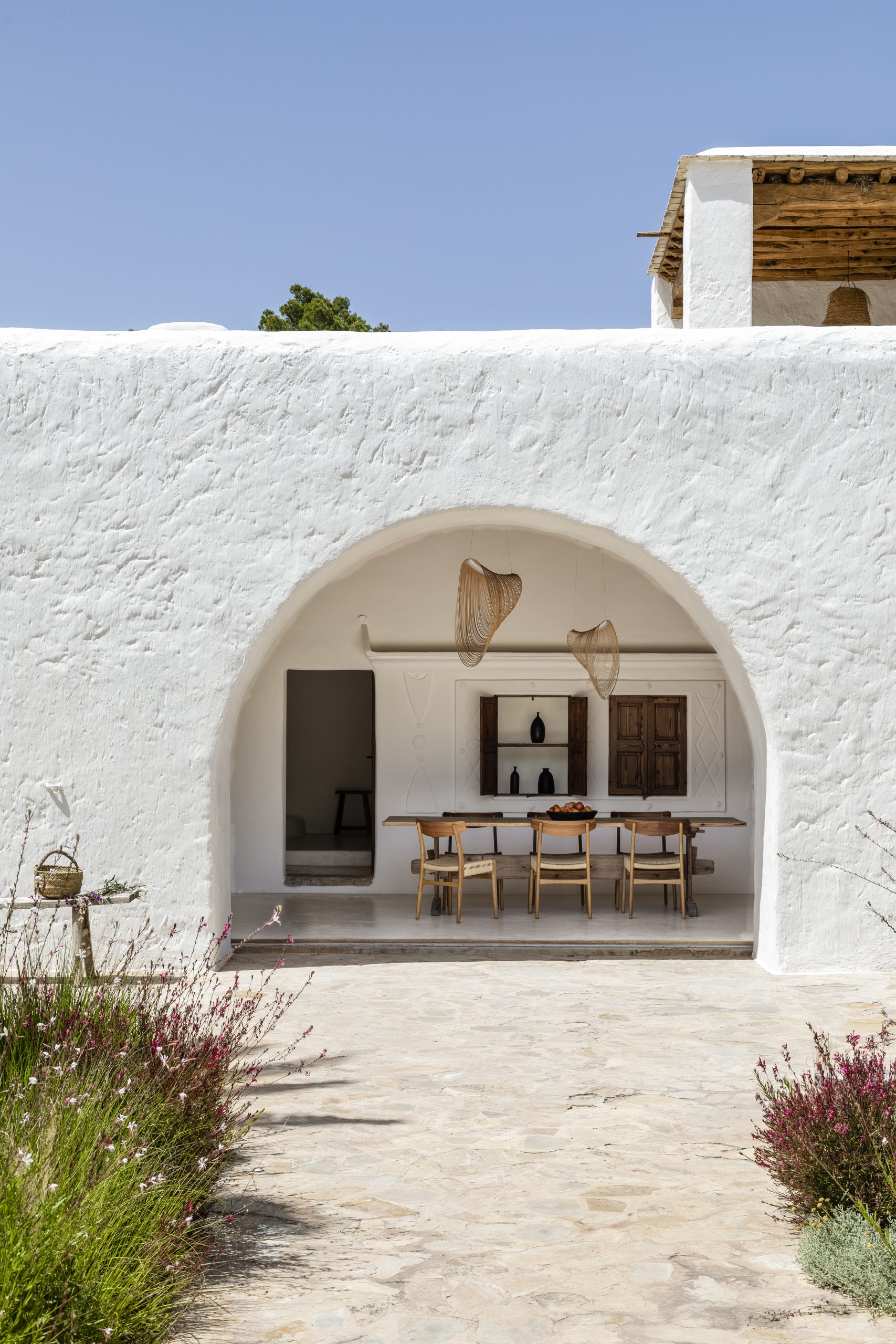 Vivienda reformada por el estudio de arquitectura KLARQ en Ibiza con muros blancos, rodeada de vegetación y con decoración rustica.